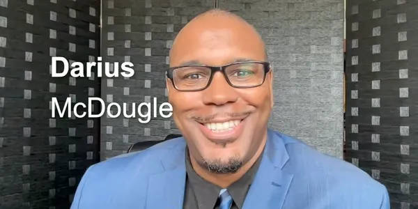 Dr. Darius McDougle smiling in a blue blazer during an interview